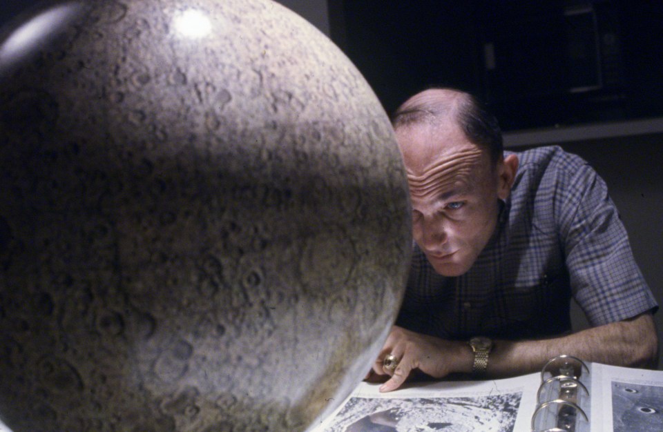 a man looking at a globe with a picture of the moon in the background