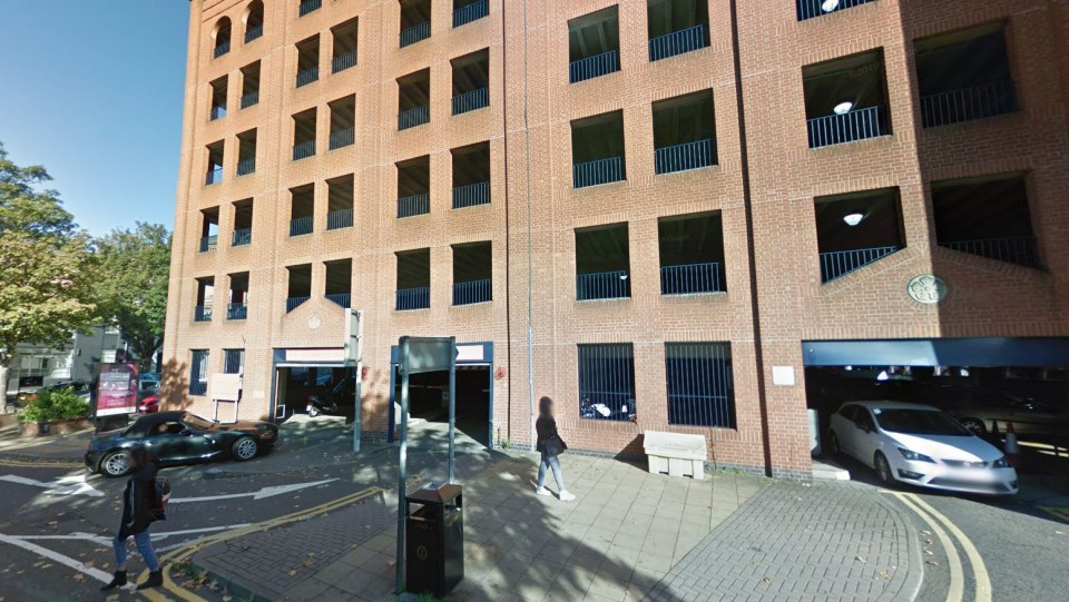 a brick building with a parking garage in front of it