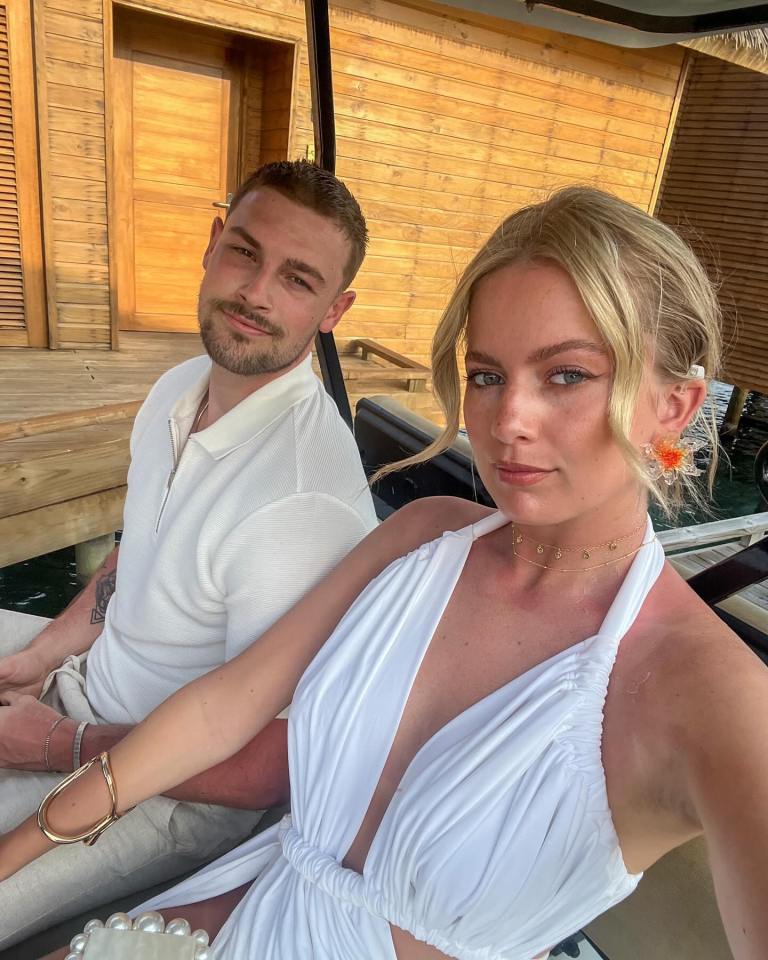 a woman in a white dress sits next to a man in a white shirt