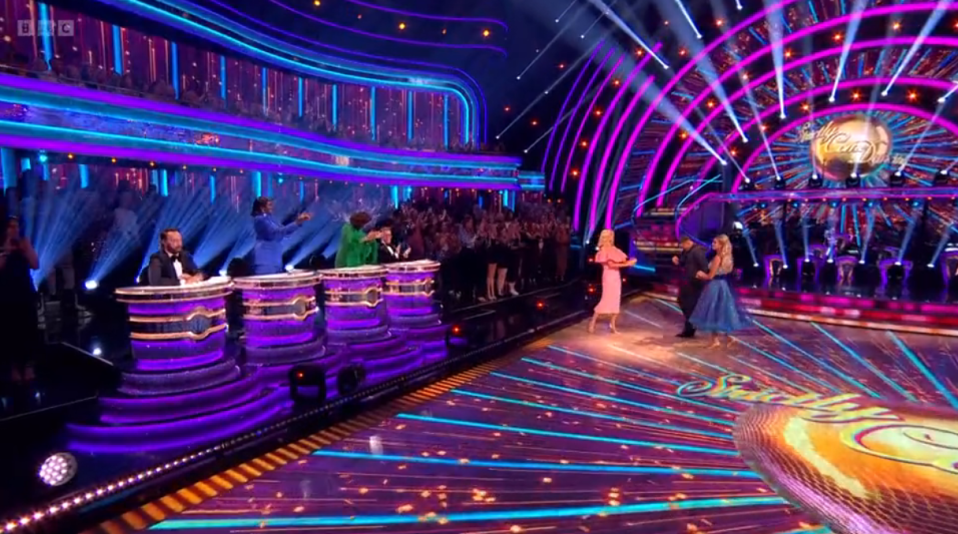 a group of people are dancing on a stage with a bbc logo in the background