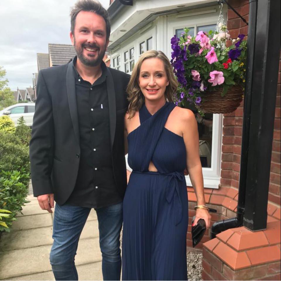 a man and a woman are posing for a picture in front of a house