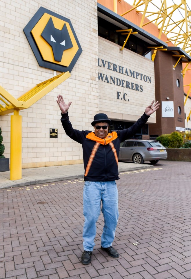 a man stands in front of the liverhampton wanderers f.c. building