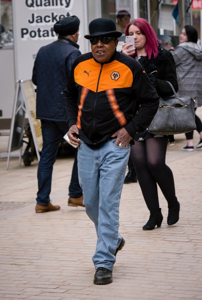 a man wearing an orange and black puma jacket walks down the street