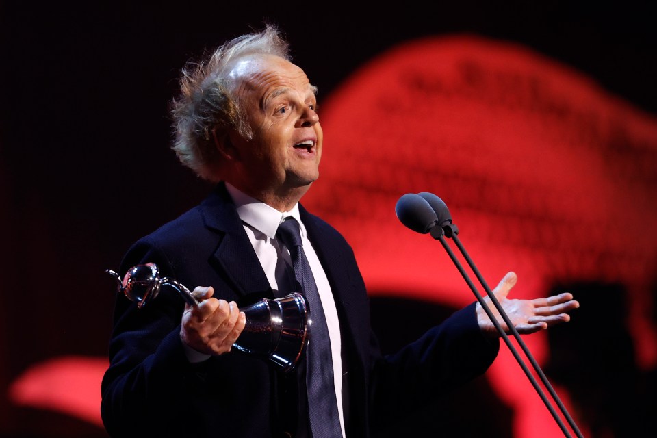 a man in a suit and tie is speaking into a microphone