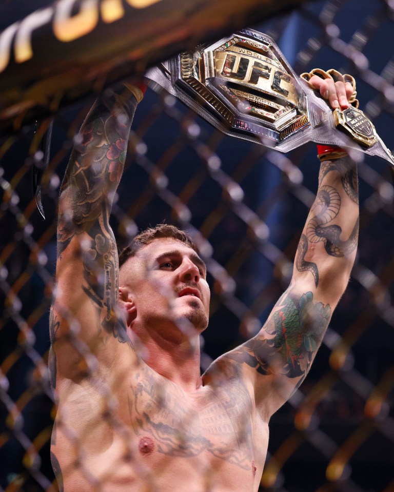 a man is holding a ufc belt over his head