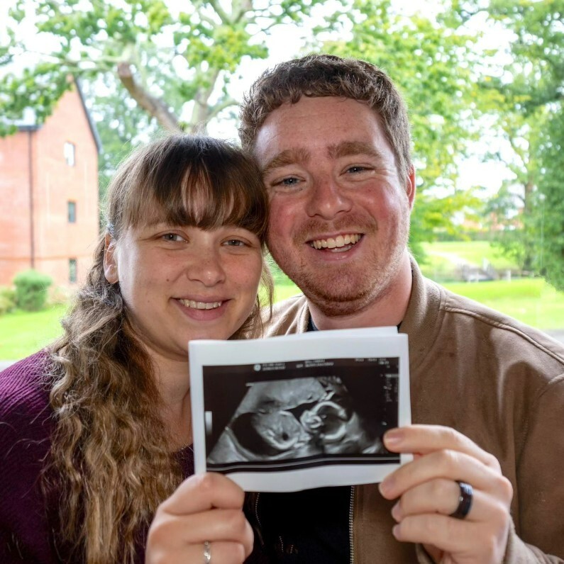 a man and woman holding up a picture of a baby