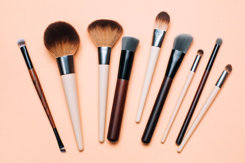 a bunch of makeup brushes on a pink background