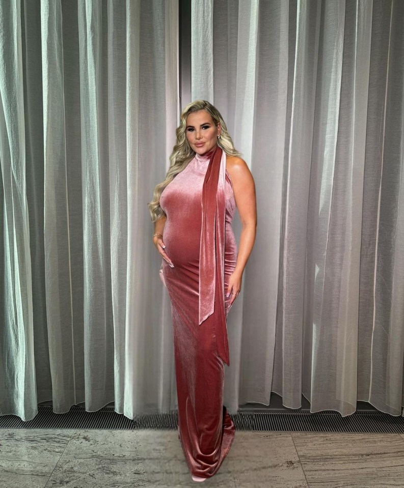 a woman in a long pink velvet dress stands in front of a white curtain