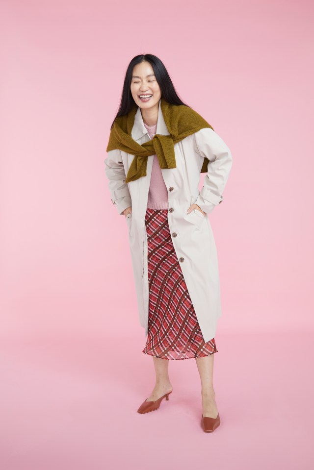 a woman wearing a trench coat and a plaid skirt