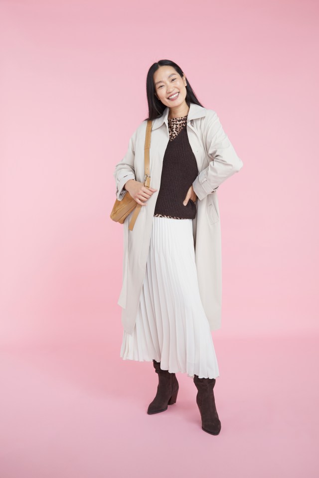 a woman wearing a trench coat and a pleated skirt