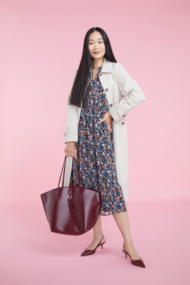 a woman in a floral dress is holding a burgundy tote bag