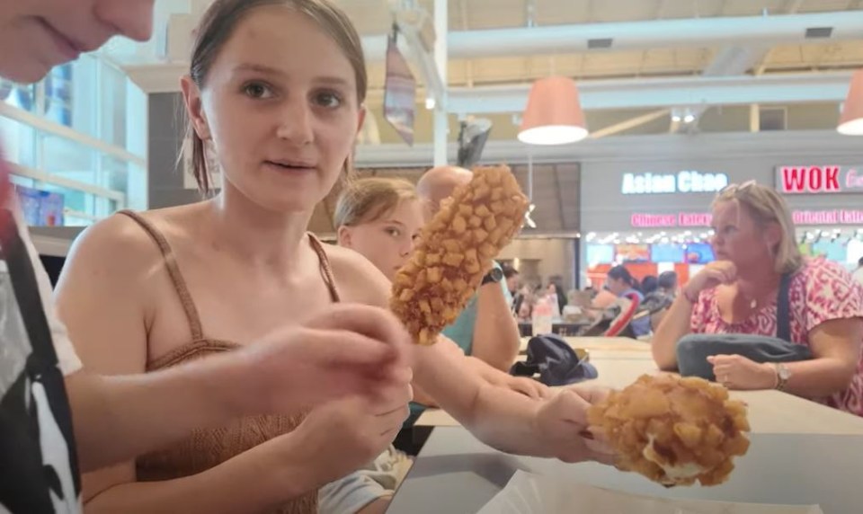 a woman holds a piece of food in front of a sign that says asian chop