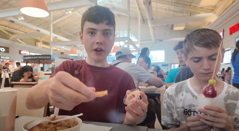 two boys are eating at a restaurant with a sign that says salad