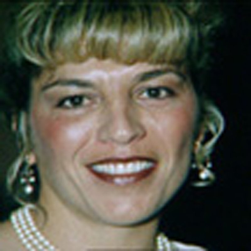 a woman wearing a pearl necklace and earrings is smiling .