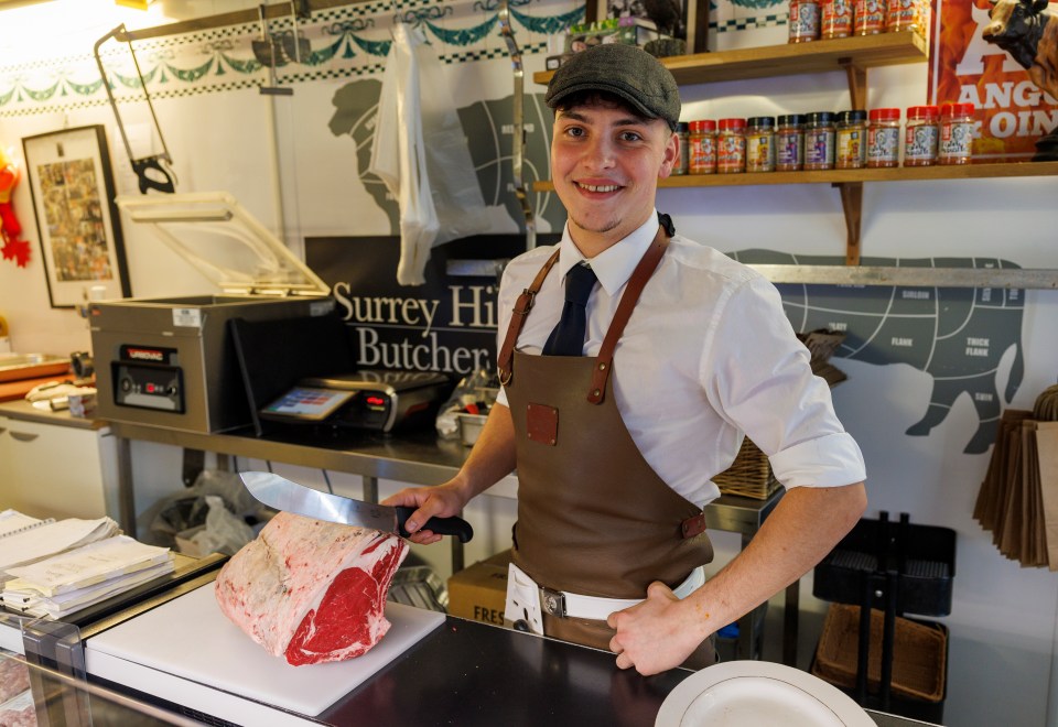 a man cutting a piece of meat in front of a sign that says surrey hill butcher