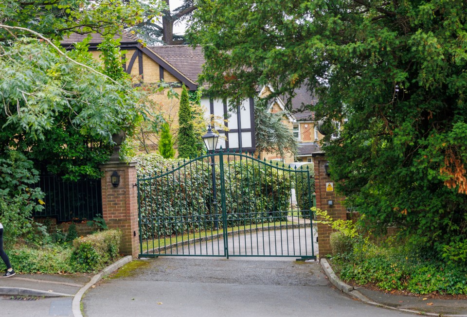 a gated entrance to a house with a yellow sign that says ' emergency exit ' on it