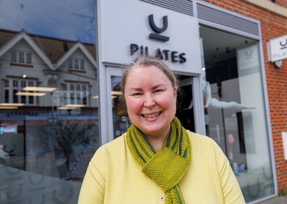 a woman smiles in front of a pilates studio