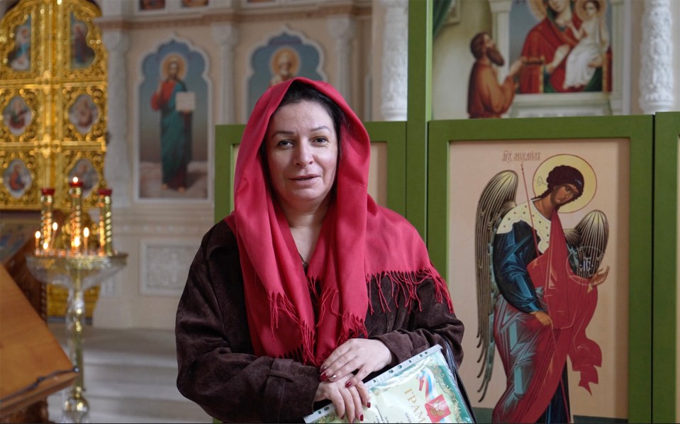 a woman in a red scarf stands in front of an icon of an angel