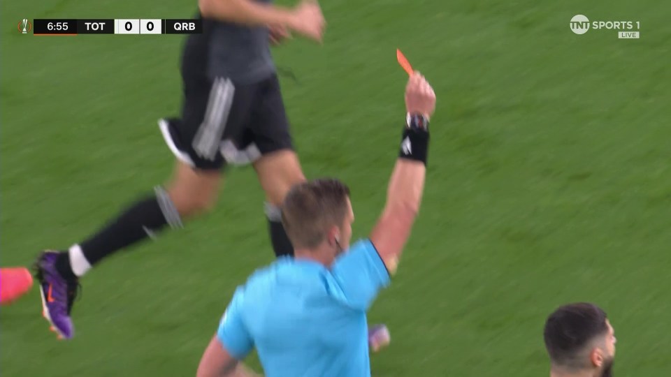 a referee holds up an orange card during a soccer game