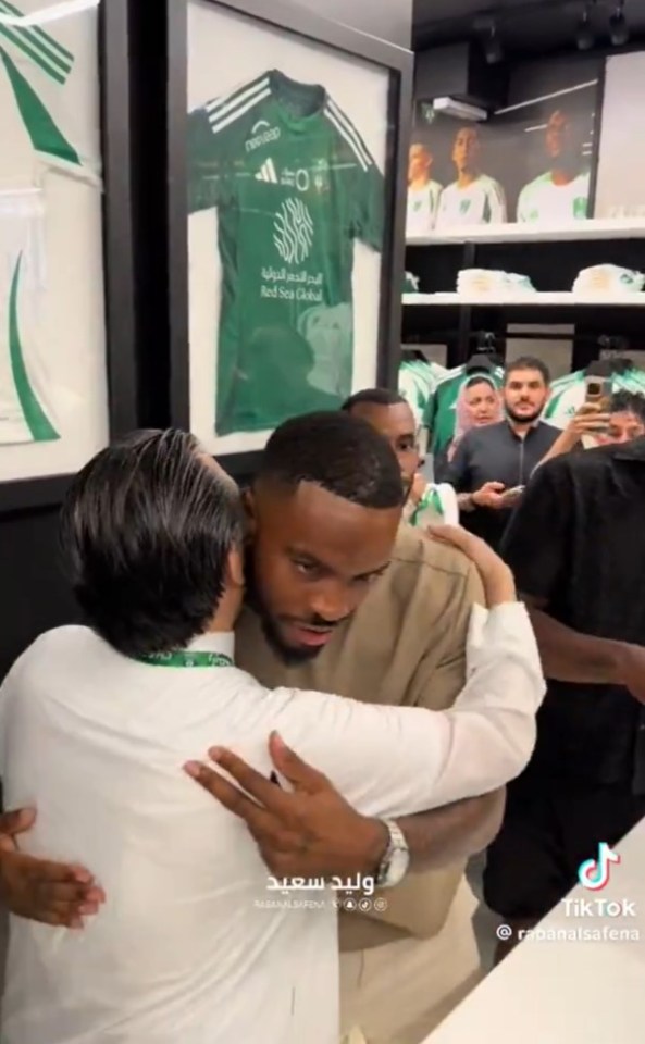 a man is hugging another man in front of a shirt that says red sea club