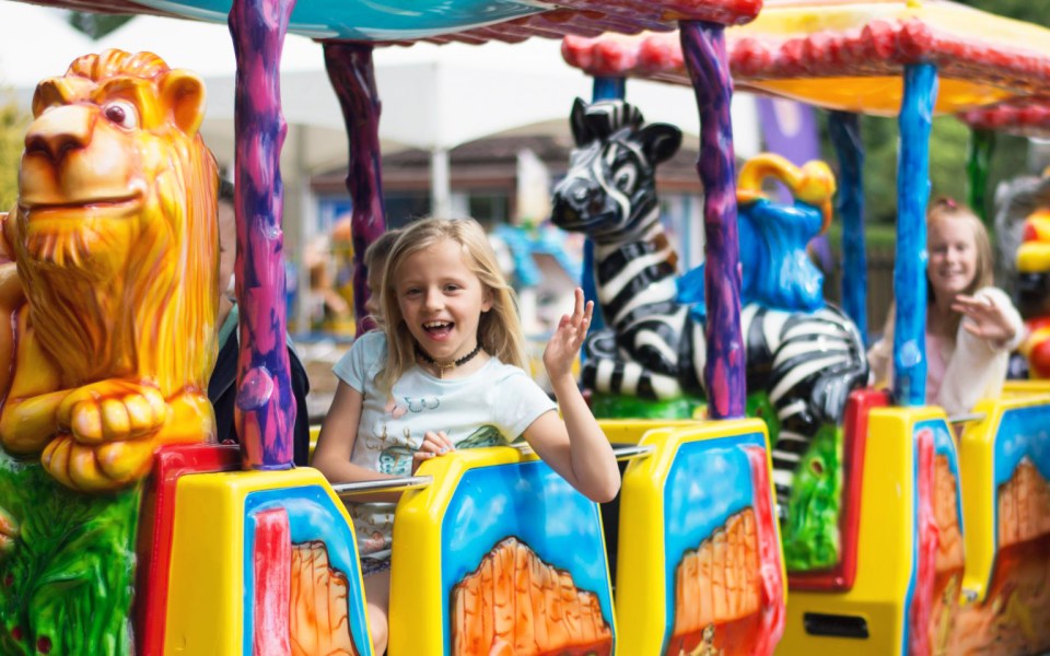 a girl riding a colorful train with animals on it