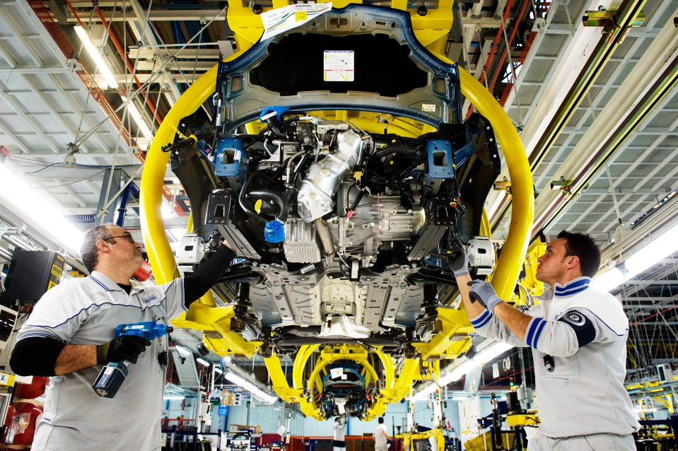 two men are working on a car in a factory