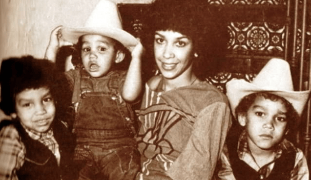 a woman is holding three children wearing cowboy hats