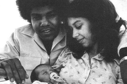 a black and white photo of a man and woman holding a baby .