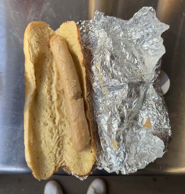 a hot dog wrapped in tin foil on a counter