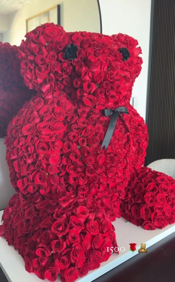 a teddy bear made of red roses sits on a table