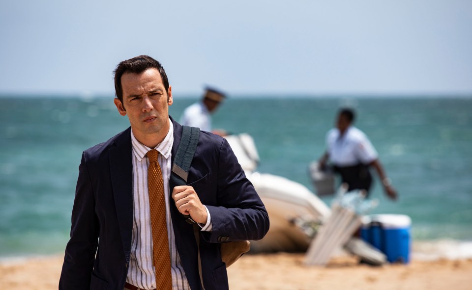 a man in a suit and tie is walking on the beach