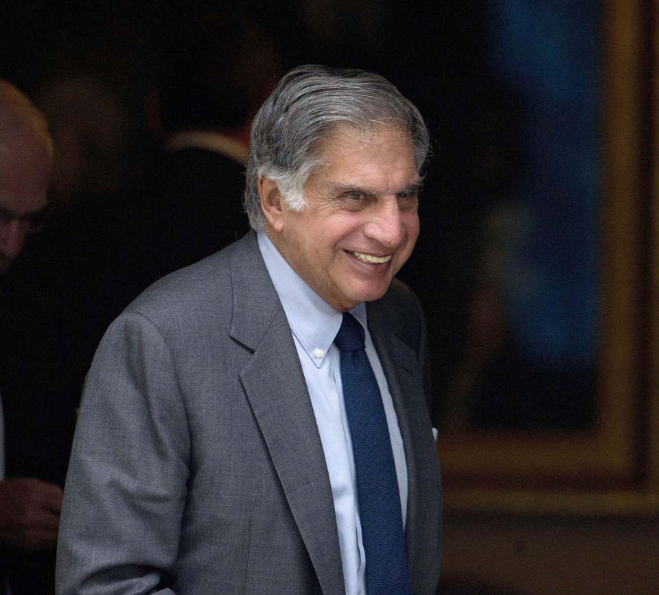 a man in a suit and tie smiles in front of a door