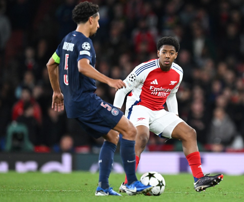 two soccer players on a field with one wearing an emirates jersey