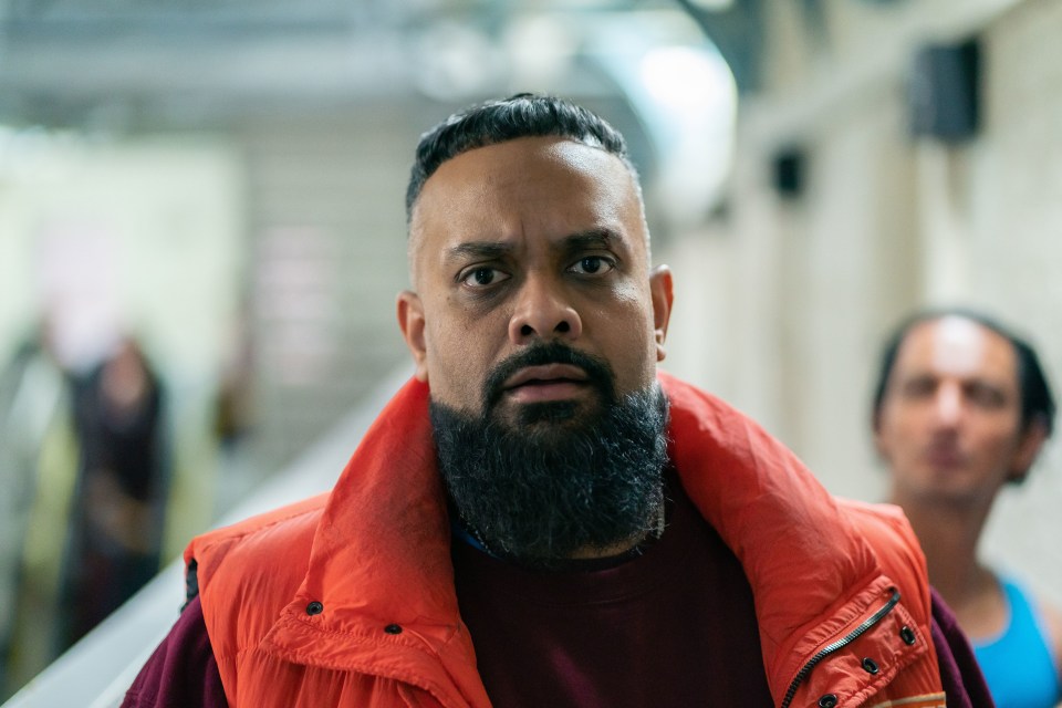 a man with a beard is wearing an orange vest