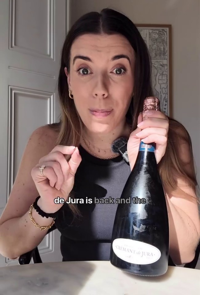 a woman is holding a bottle of de jura champagne