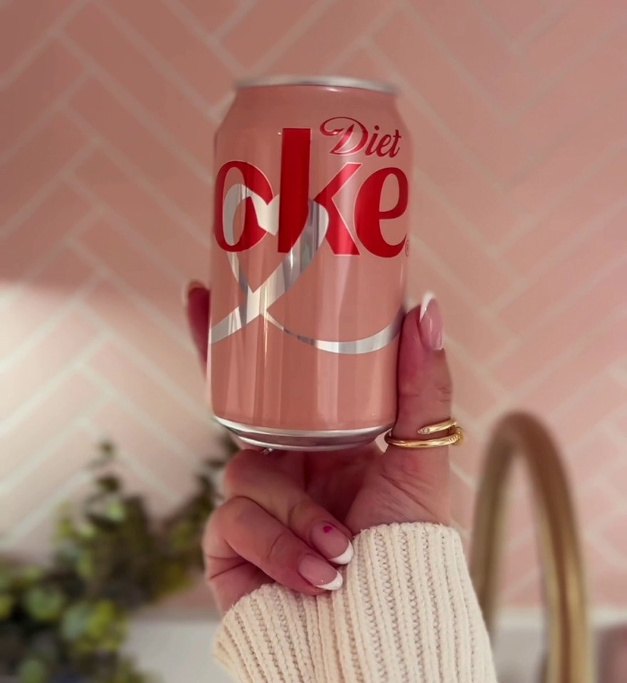 a woman is holding a can of diet coke