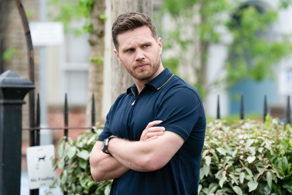 a man stands with his arms crossed in front of a no parking sign