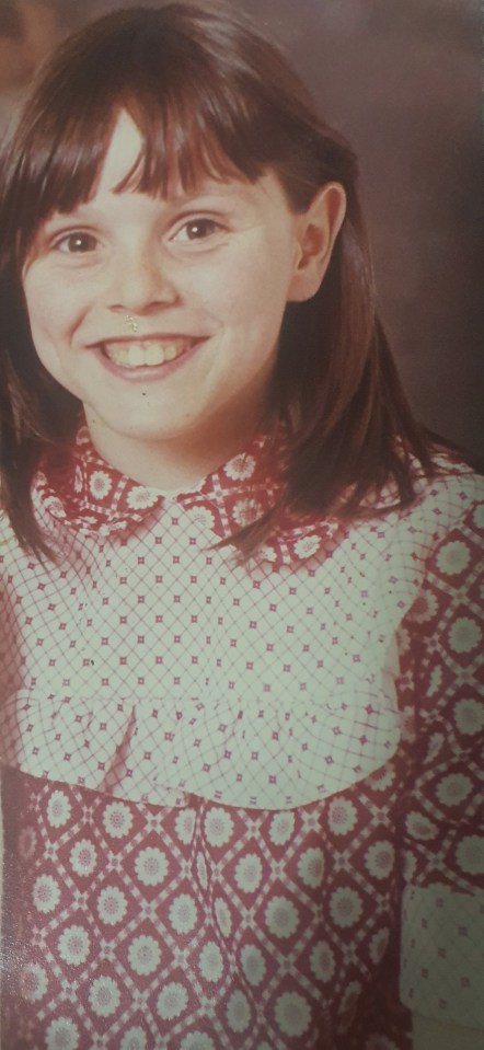 a young girl in a red and white dress smiles for the camera