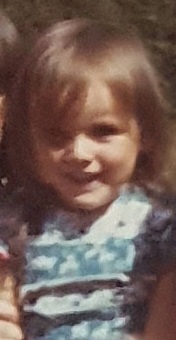 a little girl in a blue dress is smiling for the camera .