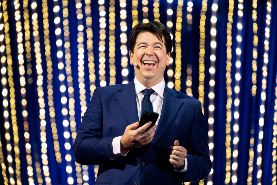 a man in a suit and tie is laughing while holding a cell phone