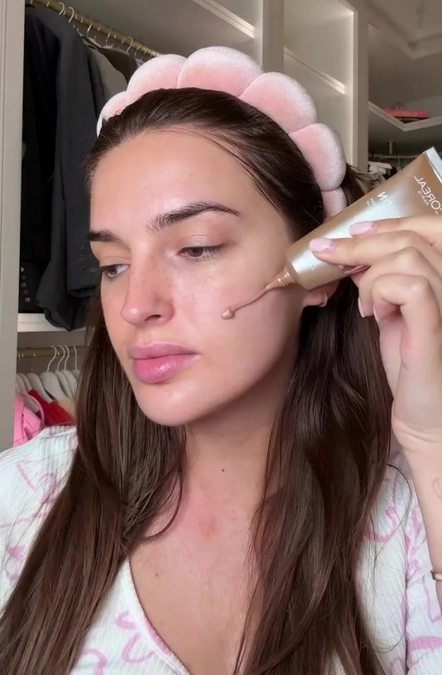 a woman wearing a headband is applying foundation to her face