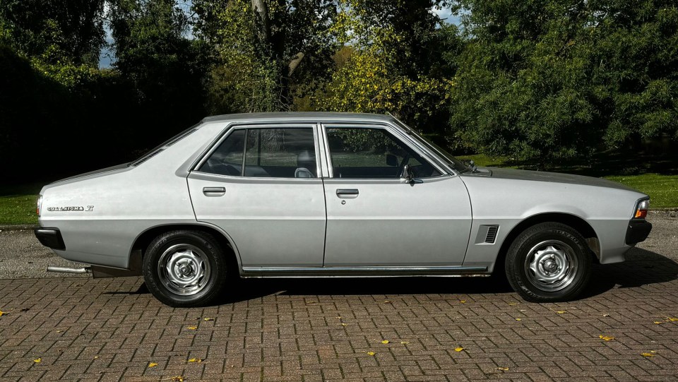 a silver mitsubishi car is parked on a brick driveway