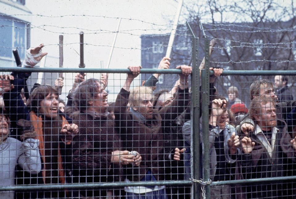 a crowd of people are behind a barbed wire fence