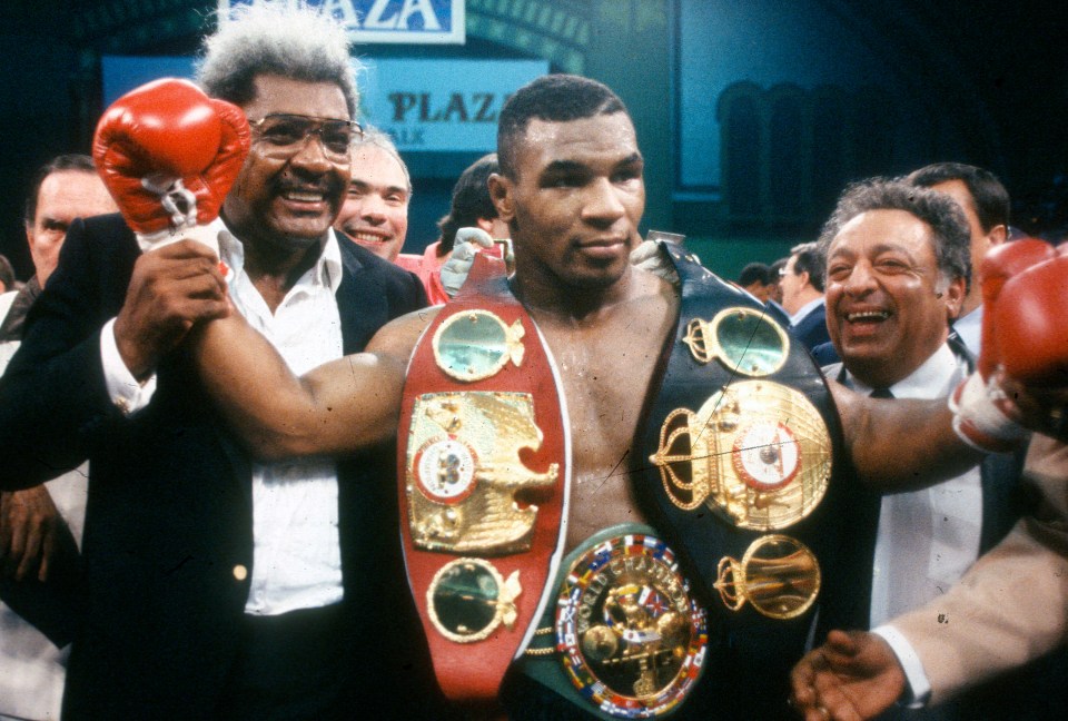 a boxer holds up his belt in front of a sign that says plaza