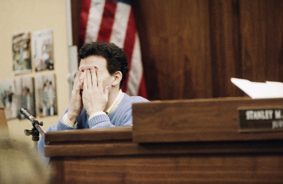 a man covering his face behind a podium that says stanley m. just