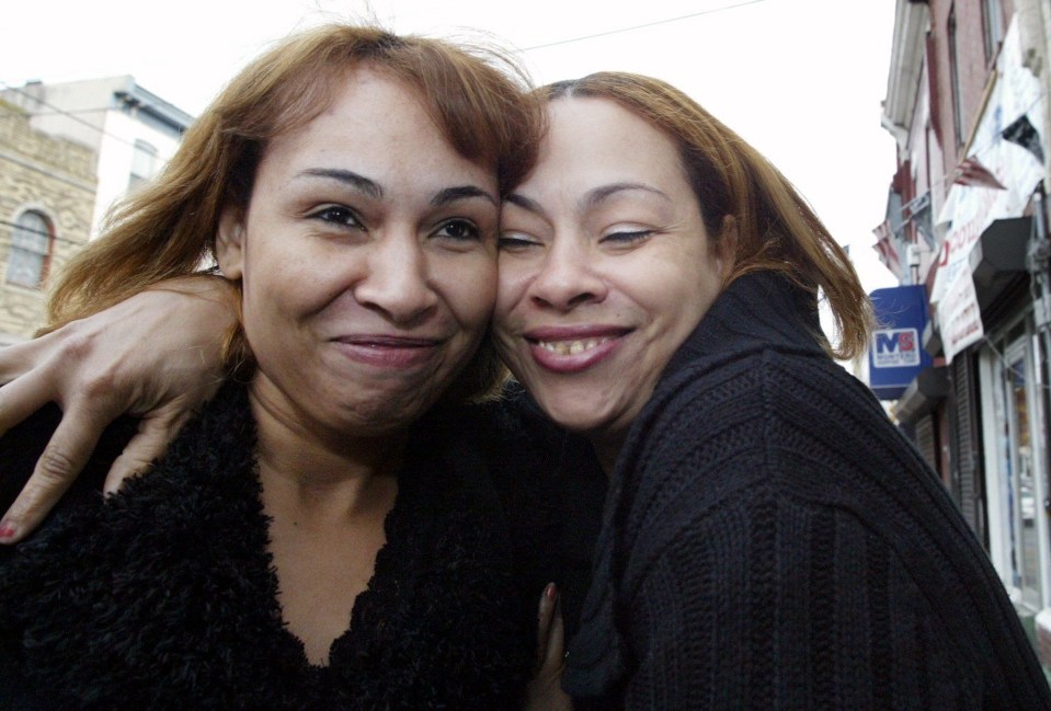 two women are posing for a picture in front of a sign that says mb