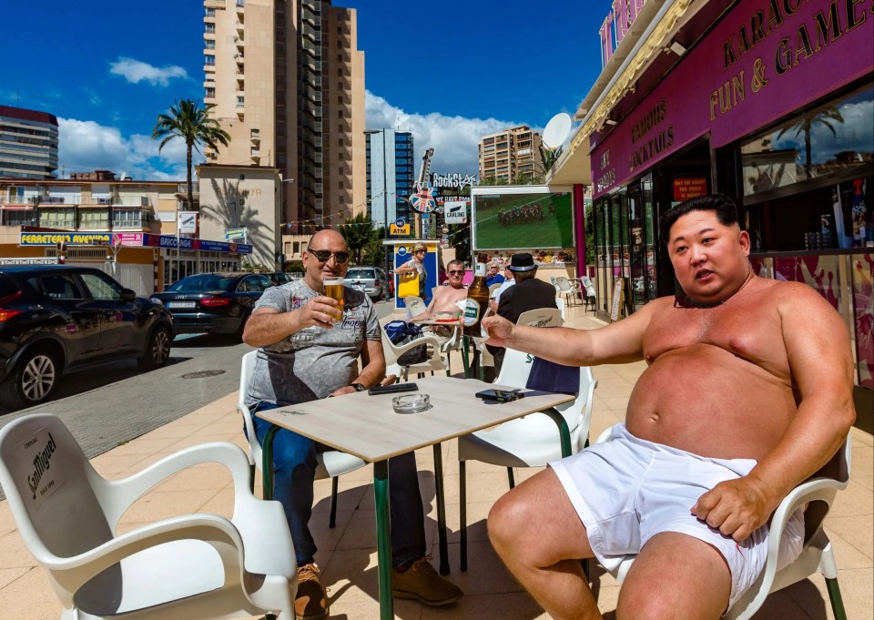 a shirtless man sits at a table in front of a karaoke bar