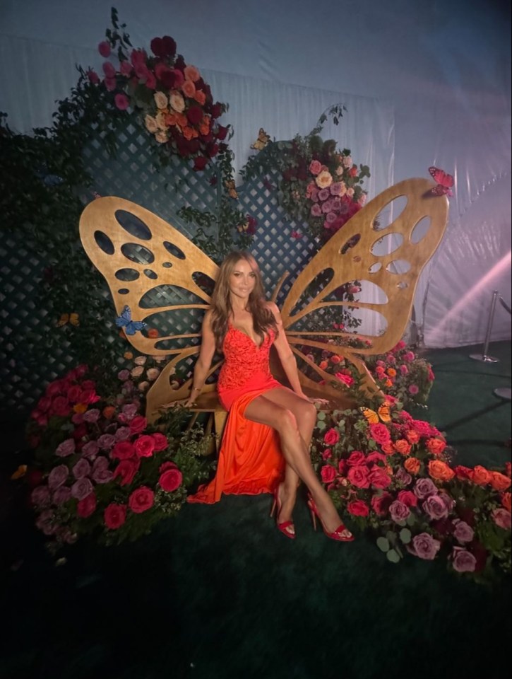 a woman in a red dress is sitting on a chair with butterfly wings