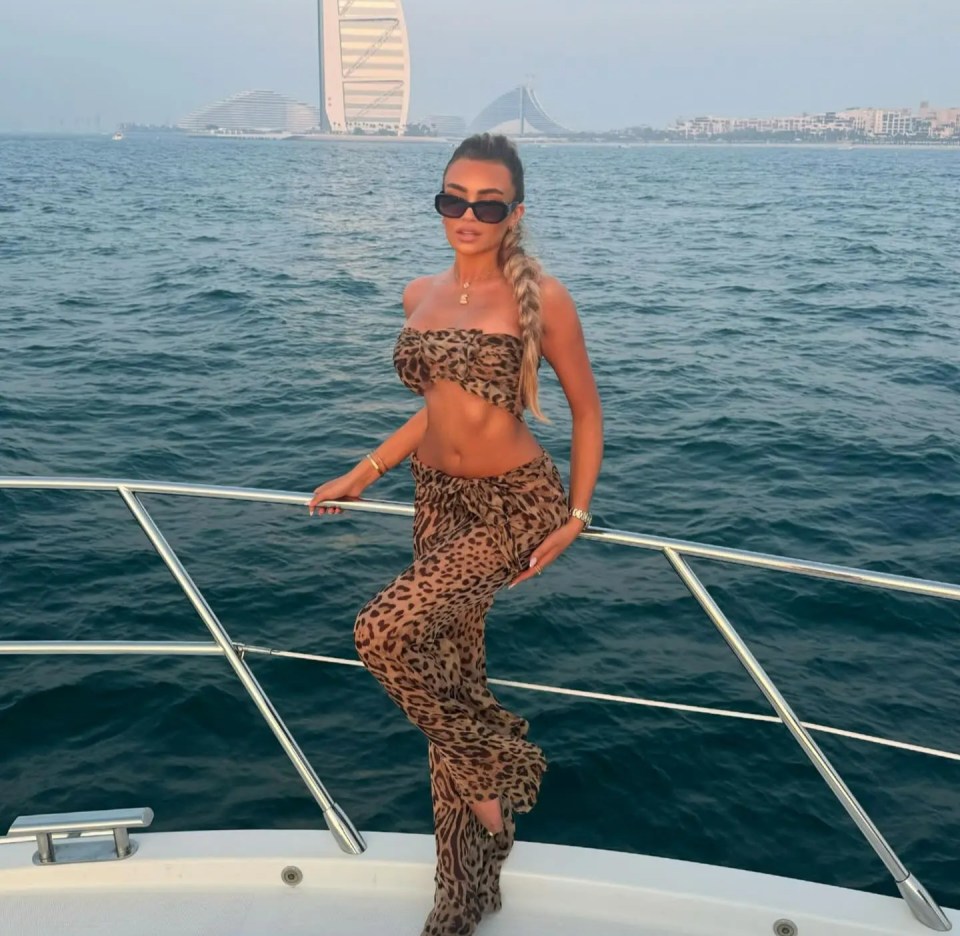 a woman in a leopard print outfit stands on a boat in the ocean