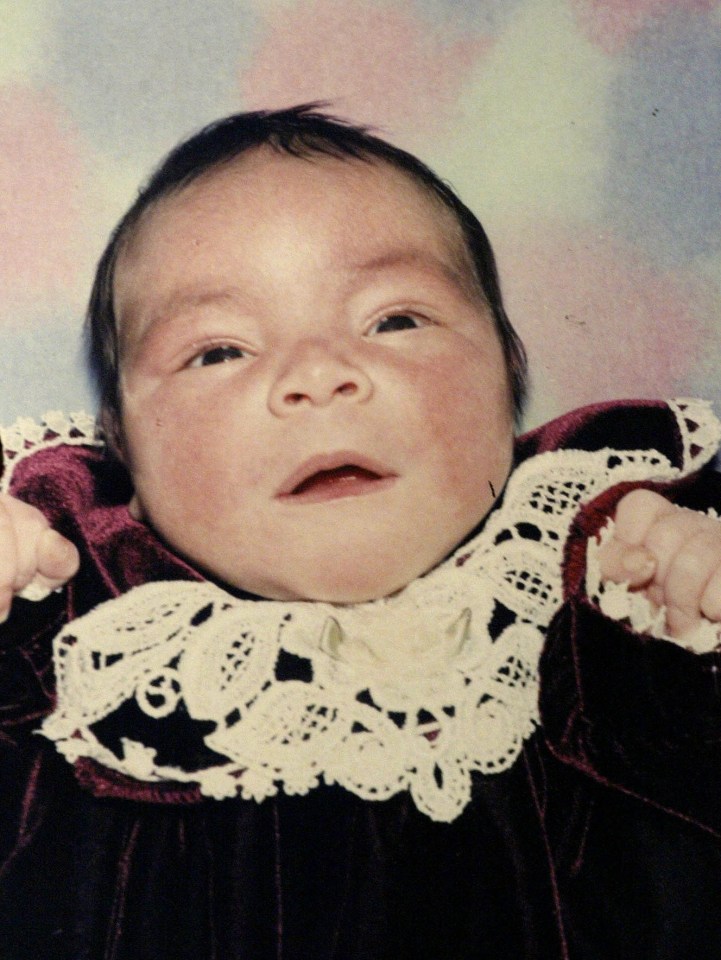 a baby wearing a lace collar and a velvet dress